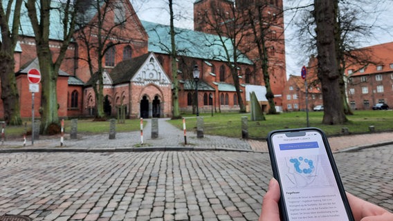 Auf einem Handy stehen Informationen über dei Lübecker Altstadt.  Foto: Lina Bande
