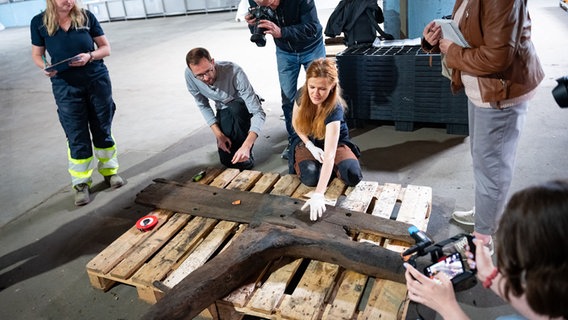 Lübeck: Archäologen erklären Journalisten die geborgenen Holzteile eines Hanseschiffes. © dpa-Bildfunk Foto: Jonas Walzberg
