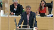 SSW-Vorsitzender Lars Harms steht am Rednerpult im Landtag. © NDR 