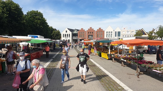 Menschen mit Mund-Nasenschutz besuchen den Wochenmarkt in Heide.  Foto: Johannes Tran