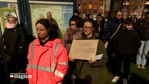 Eine Frau hält ein Pappschild mit der Aufschrift "Stoppt Mobbing!" in ihrer Hand. © NDR Foto: NDR Screenshots