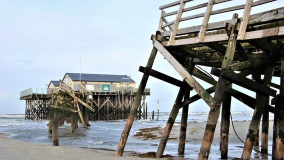 Ein kaputter Steg am Wasser, im Hintergrund eine Strandbar © Boris Pfau Foto: Boris Pfau