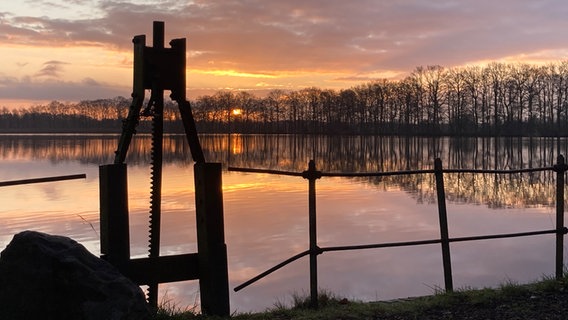 Der Bokeler See in der Morgensonne, im Vordergrund eine Metallbegrenzung. © Dawin Kasper Foto: Dawin Kasper