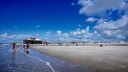 Am Strand von SPO spazieren Menschen entlang © Catarina Hey Foto: Catarina Hey