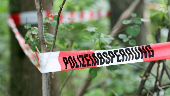 Absperrband der Polizei hängt zwischen Bäumen in einem Wald © dpa Foto: Bodo Marks