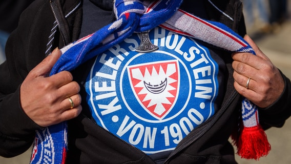 Ein Fan des KSV Holstein zeigt vor dem Holstein-Stadion das Emblem seines Vereins auf seinem Shirt. © dpa-Bildfunk Foto: Frank Molter