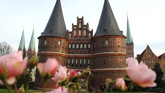 Blick auf das Lübecker Holstentor mit Rosen im Vordergrund. © dpa Foto: Wolfgang Langenstrassen