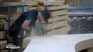 Ein Handwerker sägt eine Holzplatte. © NDR 