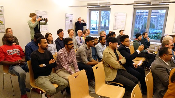 Eine Gruppe Menschen, darunter Studenten aus Afrika, Asien und Südamerika, sitzen in einem Raum der Hochschule Flensburg. © NDR Foto: Peer-Axel Kroeske