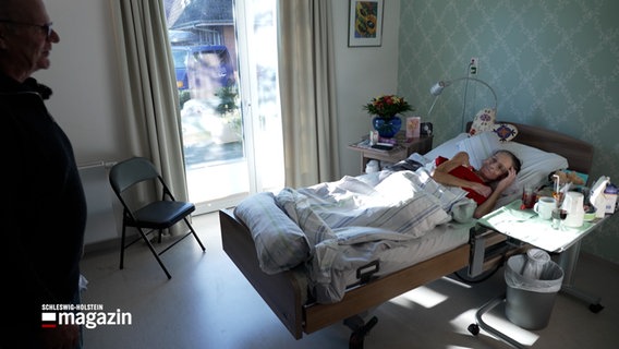 Ein Mann besucht eine Frau in einem Hospitz. © NDR 