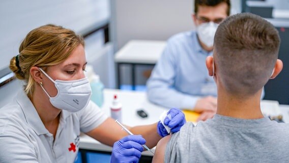 Eine Junge wird von einer Mitarbeiterin vom Deutschen Roten Kreuz geimpft. © picture alliance/dpa Foto: Axel Heimken