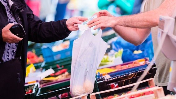 Eine Kundin bezahlt auf einem Wochenmarkt am Obst- und Gemüsestand mit 20 Euro. © dpa-Bildfunk Foto: Christoph Soeder