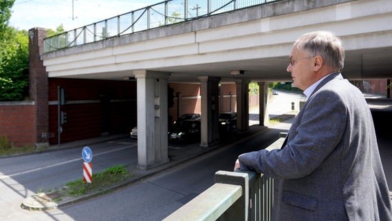 Ein Mann steht auf einer Brücke und blickt auf die Straße. © NDR Foto: Elin Halvorsen