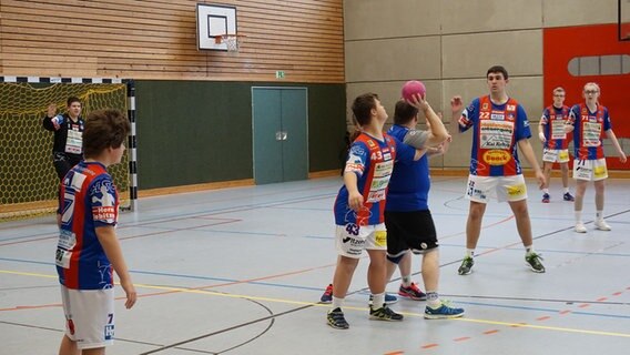 Ein Handballspieler versucht sich am Kreis gegen zwei Spieler durchzusetzen. © NDR Foto: Samir Chawki
