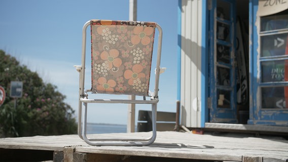 Ein Klappstuhl steht außerhalb der Surfschule © NDR Foto: Dominik Dührsen