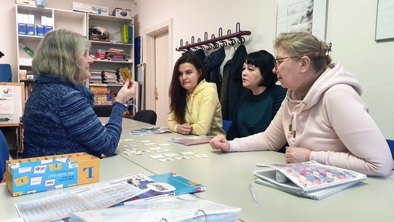 Drei Frauen sitzen an einem Tisch mit einer ehrenamtlichen Lehrerin bei einem Sprachkurs beim Bad Oldesloer Verein Kaktus. © NDR Foto: Johannes Tran