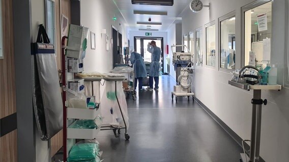 Zwei Mitarbeiter stehen in Schutzkleidung im Flur der Intensivstation des UKSH. Zwei Mitarbeiter stehen in Schutzkleidung im Flur der Intensivstation des UKSH. © NDR Foto: Cassandra Arden