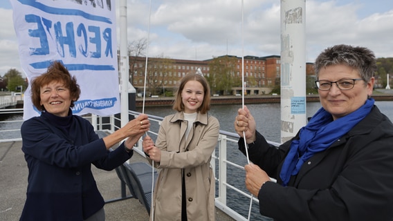 Vor dem Landtag in Kiel hissen drei Frauen eine Flagge © Oke Jens Foto: Oke Jens