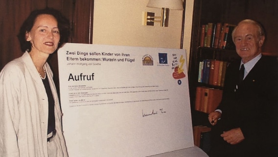 Eine Frau und der Bundespräsident Johannes Rau stehen vor einem Plakat © DKSBLVSH Foto: DKSBLVSH