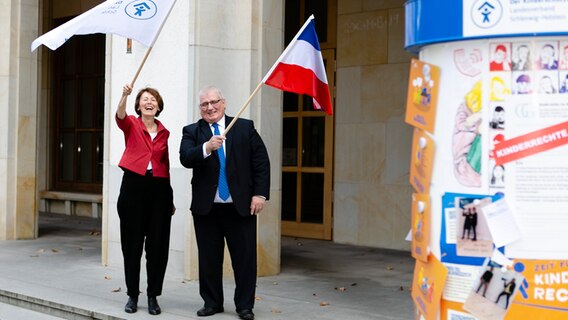 Eine Frau und ein Mann schwenken Flaggen vor dem landtag in Schleswig-Holstein © DKSB LV SH Foto: Frank Molter