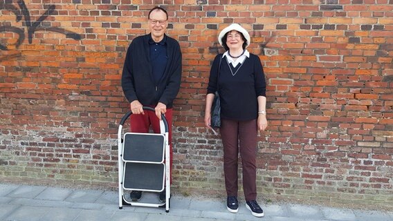 Wolfgang und Beate Jandt vom Geschichtsverein Niebüll stehen vor einer Mauer. Wolfgang und Beate Jandt vom Geschichtsverein Niebüll stehen vor einer Mauer. © NDR Foto: Lukas Knauer
