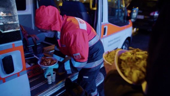 Eine Helferin gibt am Kältebus Essen aus. © NDR Foto: NDR