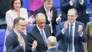 Der scheidende Bundeskanzler Olaf Scholz (M, von hinten, SPD) gratuliert dem neu gewählten Bundeskanzler Friedrich Merz (M, CDU) zu seiner Wahl. im Bundestag. Daneben applaudieren Jens Spahn (l, CDU), Unionsfraktionsvorsitzender, designierter und Alexander Dobrindt (r, CSU), designierter Bundesinnenminister. Der Kanzlerkandidat von CDU, CSU und SPD, Merz, erhielt im zweiten Wahlgang die nötige Stimmenzahl. © dpa-Bildfunk Foto: Michael Kappeler