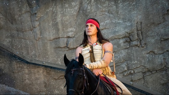 Alexander Klaws als Winnetou sitzt auf einem Pferd vor den Felsen des Kalkbergs während der Premiere "Winnetou I - Blutsbrüder" der 70. Saison der Karl-May-Spiele in Bad Segeberg. ©  Jonas Walzberg/dpa Foto: Jonas Walzberg