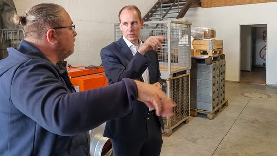 Zwei Männer unterhalten sich in einem Lagerraum. Zwei Männer unterhalten sich in einem Lagerraum. © NDR Foto: Julian Marxen