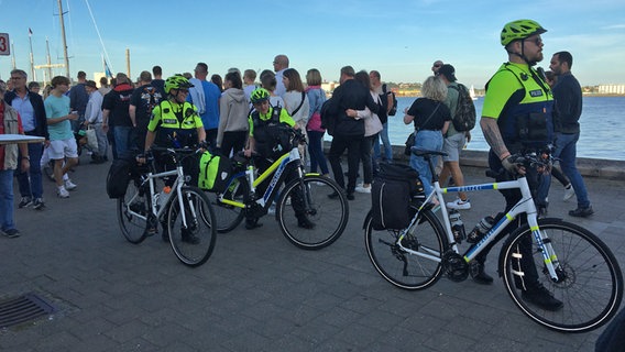 Vier Beamten der der Fahrradstaffel der Polizei sind mit ihren Fahrrädern an der Kiellinie unterwegs. © NDR Foto: Friedericke Schneider