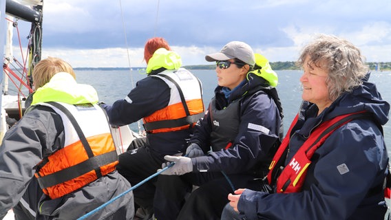 Die Crewmitglieder sitzen am Bord des Segelbootes "Helga". © NDR Foto: Marina Heller