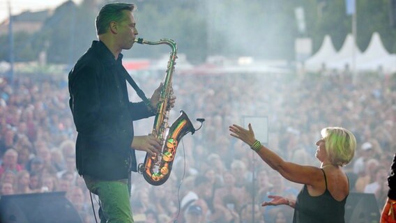 Hanne Pries, Sängerin der Band Tiffany, zeigt bei einem Konzert auf der NDR Bühne am Ostseekai auf der Kieler Woche auf den Saxophonisten der Band: Joachim Kopp. © NDR Foto: Björn Schaller
