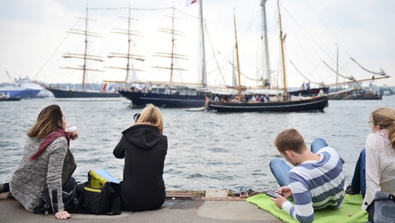 Menschen auf einem Anlegersteg beobachten die Windjammerparade. © NDR Foto: Yosua Pandelaki