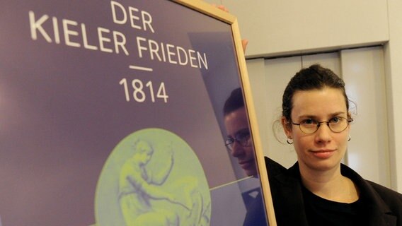 Kuratorin Sonja Kinzler zeigt im Stadtmuseum von Kiel ein Austellungsplakat © picture alliance / dpa Foto: Carsten Rehder