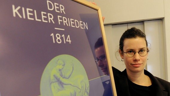 Kuratorin Sonja Kinzler zeigt im Stadtmuseum von Kiel ein Austellungsplakat © dpa Bildfunk Foto: Carsten Rehder