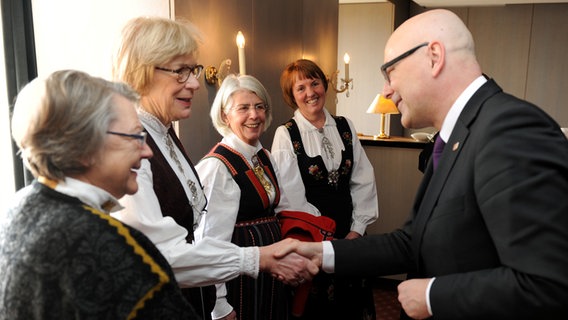 Ministerpräsident Torsten Albig begrüßt norwegische Besucherinnen in Landestrachten © picture alliance / dpa Foto: Carsten Rehder