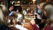 Mehrere Kinder sitzen in einem Restaurante und essen Pizza. © NDR Foto: Nadine Dietrich