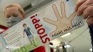 Eine Frau hält einen Comic in der Hand, der übergriffiges Verhalten an Kindern zum Thema hat. © NDR 