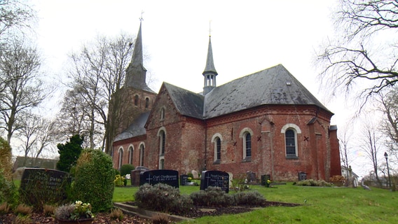Grabsteine sind vor dem Kirchengebäude in Oldeswort zu sehen. © NDR 
