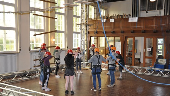 Eine Gruppe von Leuten stehen unter einem Kletterparcours, der sich in einer Kirche befindet.  Foto: Peter Bartelt