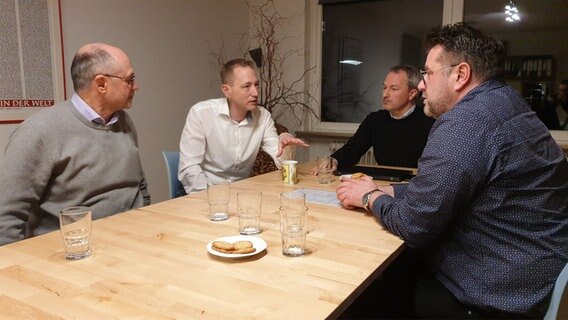 Vier Männer sitzen an einem Tisch und unterhalten sich. © NDR Foto: Johannes Tran