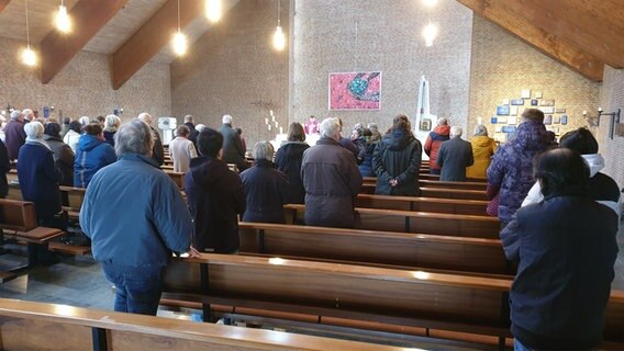 Menschen nehmen an einem Gottesdienst in einer Kirche teil. © NDR Foto: Johannes Tran