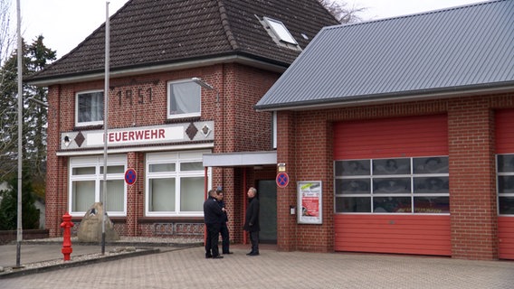 Drei Männer stehen vor dem Feuerwehrhaus der Gemeinde Kisdorf. © NDR 
