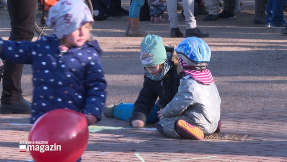 Kinder sitzen auf dem Boden und spielen mit Kreide. © NDR 