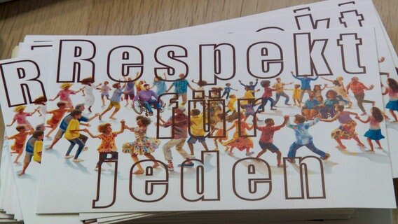Ein Stappel Papierkarten mit dem Schriftzug "Respekt für jeden" liegt auf einem Tisch in der AWO-Kita Meldorf. © NDR 