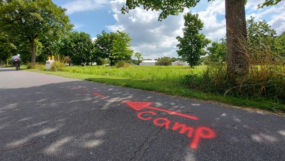 Mit roter Farbe steht auf einem Radweg "Camp" mit einem Pfeil der nach links zeigt. © NDR Foto: Laura Albus