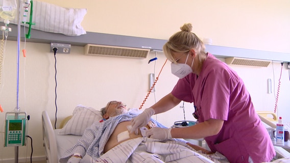 Eine Krankenschwester versorgt einen Patienten. © NDR 