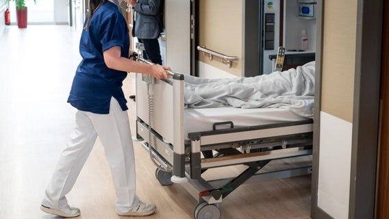 Eine Pflegerin schiebt einen Patienten in ein Krankenzimmer. © picture alliance / Flashpic | Jens Krick Foto: Jens Krick