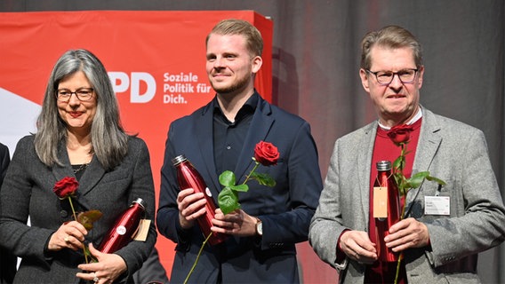 Nina Scheer (links), Tim Klüssendorf (mitte) und Ralf Stegner (rechts) halten rote Rosen in Händen, nachdem sie auf die ersten drei Listenplätze der SPD Schleswig-Holstein für die Bundestagswahl 2025 gewählt wurden. Nina Scheer (links), Tim Klüssendorf (mitte) und Ralf Stegner (rechts) halten rote Rosen in Händen, nachdem sie auf die ersten drei Listenplätze der SPD Schleswig-Holstein für die Bundestagswahl 2025 gewählt wurden. © picture alliance/dpa Foto: Felix Müschen