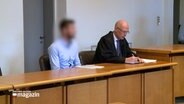 Ein Angeklagter sitzt im Gerichtssaal neben seinem Anwalt. © NDR 